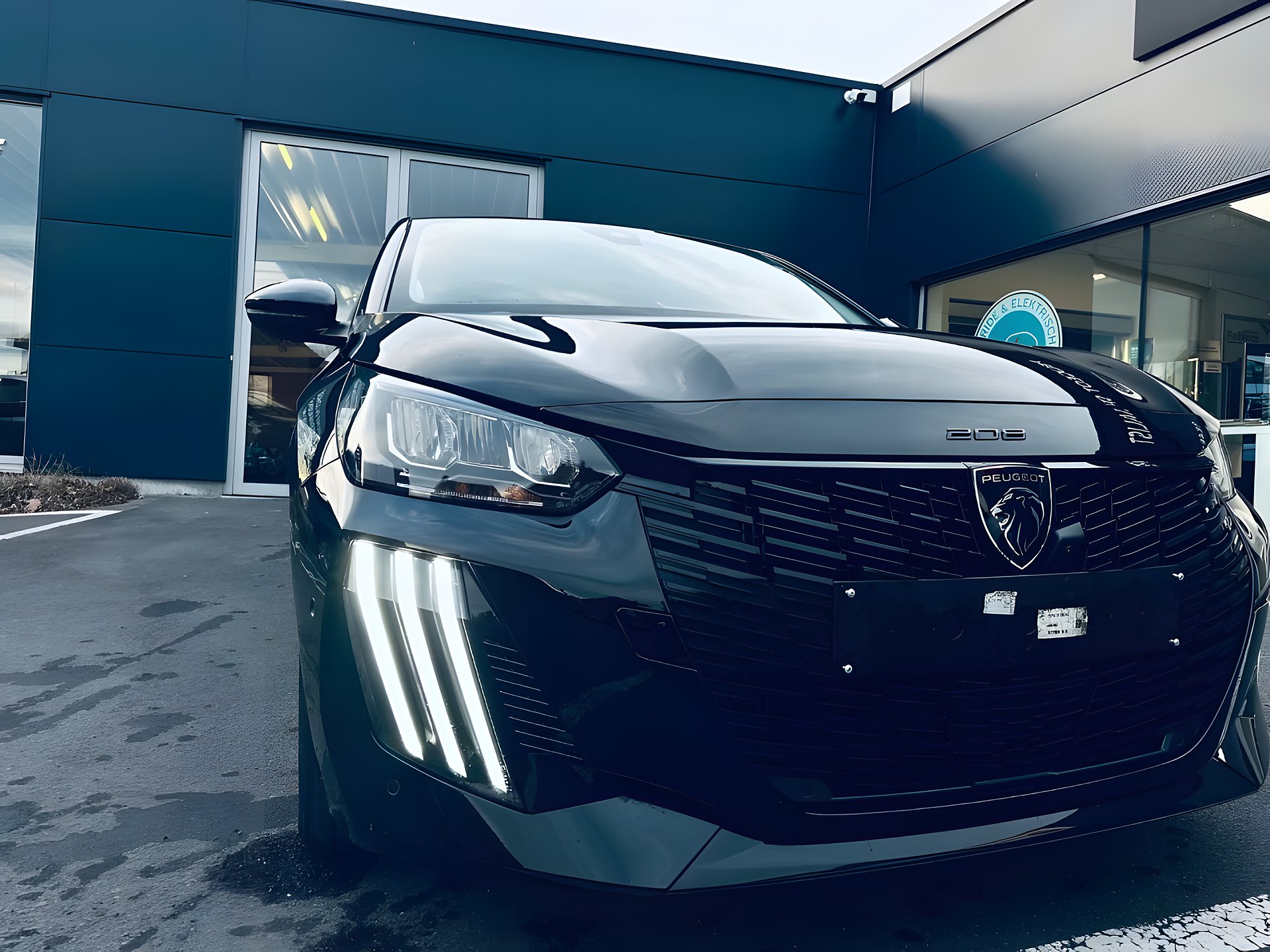 Een Peugeot 208 voor de showroom van Garage De Maeyer bij valavond